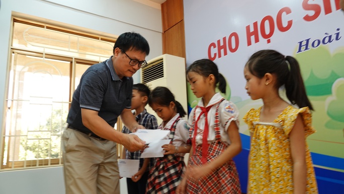 Đại diện Chi hội Nhà báo thường trú tại Bình Định tặng quà cho các em học sinh vượt khó học giỏi. Ảnh: Đức Anh