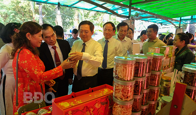Lãnh đạo tỉnh và Hội đồng hương Bình Định tại TP Hồ Chí Minh tham quan gian hàng của HTX Sản xuất, kinh doanh hải sản Hương Thanh (xã Nhơn Lý, TP Quy Nhơn) trong khu trưng bày sản phẩm Bình Định tại Ngày hội. Ảnh: NGỌC NHUẬN      